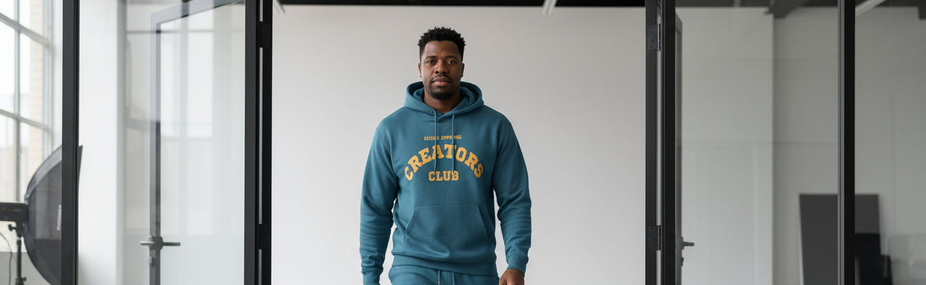 Man wearing a blue tracksuit with 'Creators CLUB' text in a modern interior setting